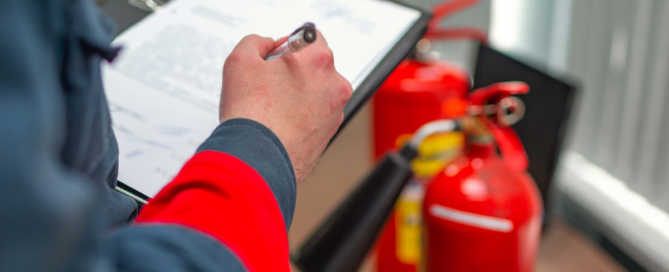 person with notepad making notes in front of fire extinguishers