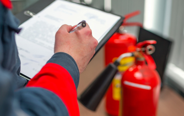 person with notepad making notes in front of fire extinguishers